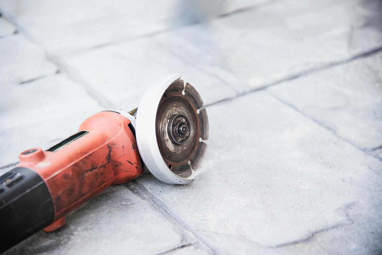 used electrical angle grinder on gray cement floor, famous construction