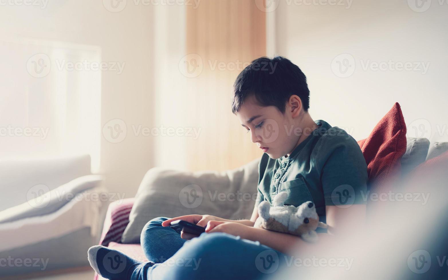 Education concept,School kid using mobile phone readying story from internet,Boy studying online learning at home,Child using cell phone playing game or chatting with friends, Homeschooling photo