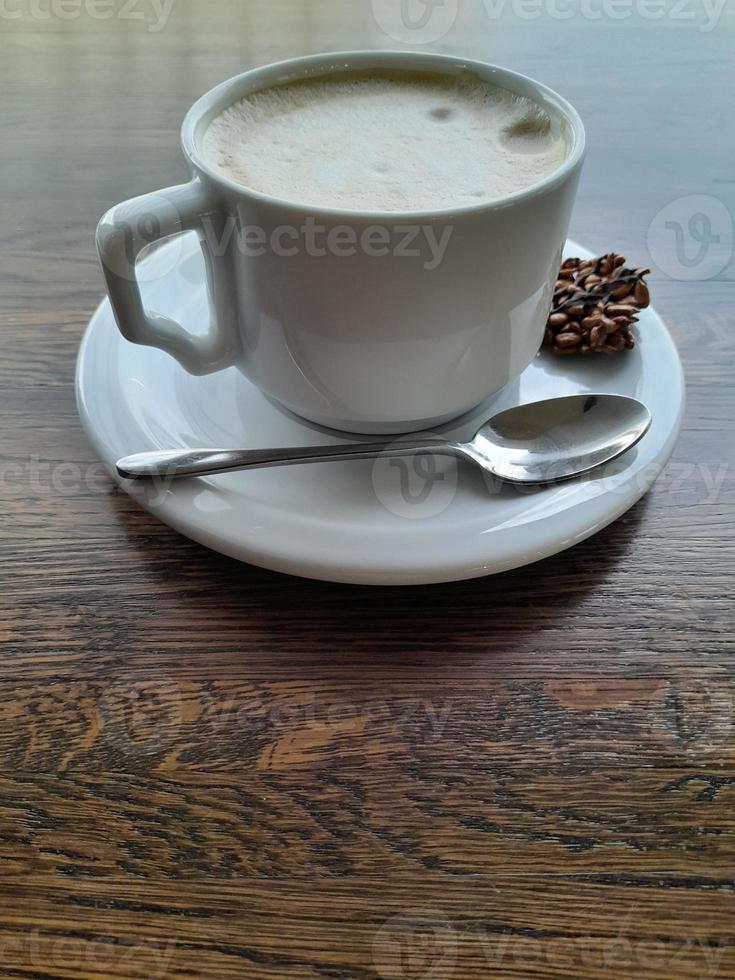 Cup of coffee on a wooden table. White cup with saucer and spoon photo
