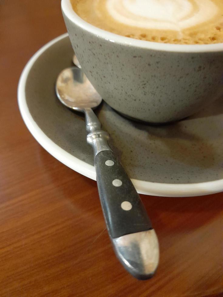 taza de café en un de madera mesa. gris taza con platillo y cuchara foto