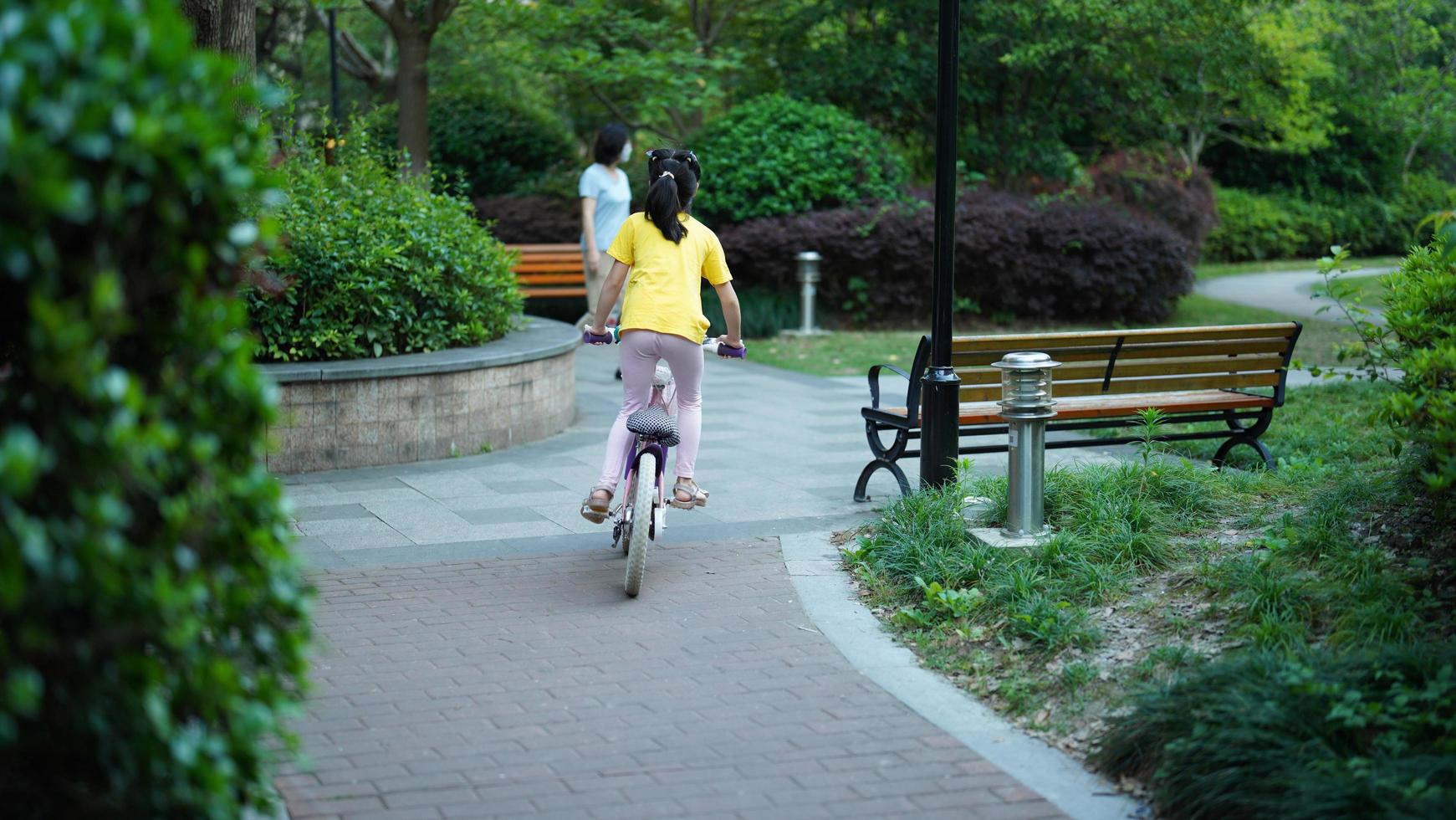 Shanghai City, China, 2022 - A little girl riding the bicycle in the garden in summer photo
