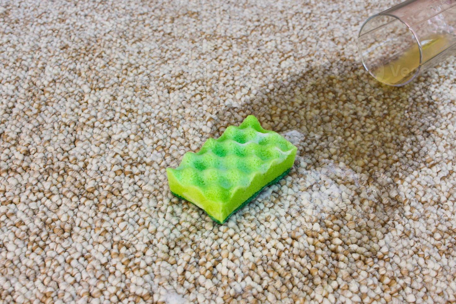 Glass of orange juice fell on carpet. Drink spilled on floor. Sponge and detergent. photo
