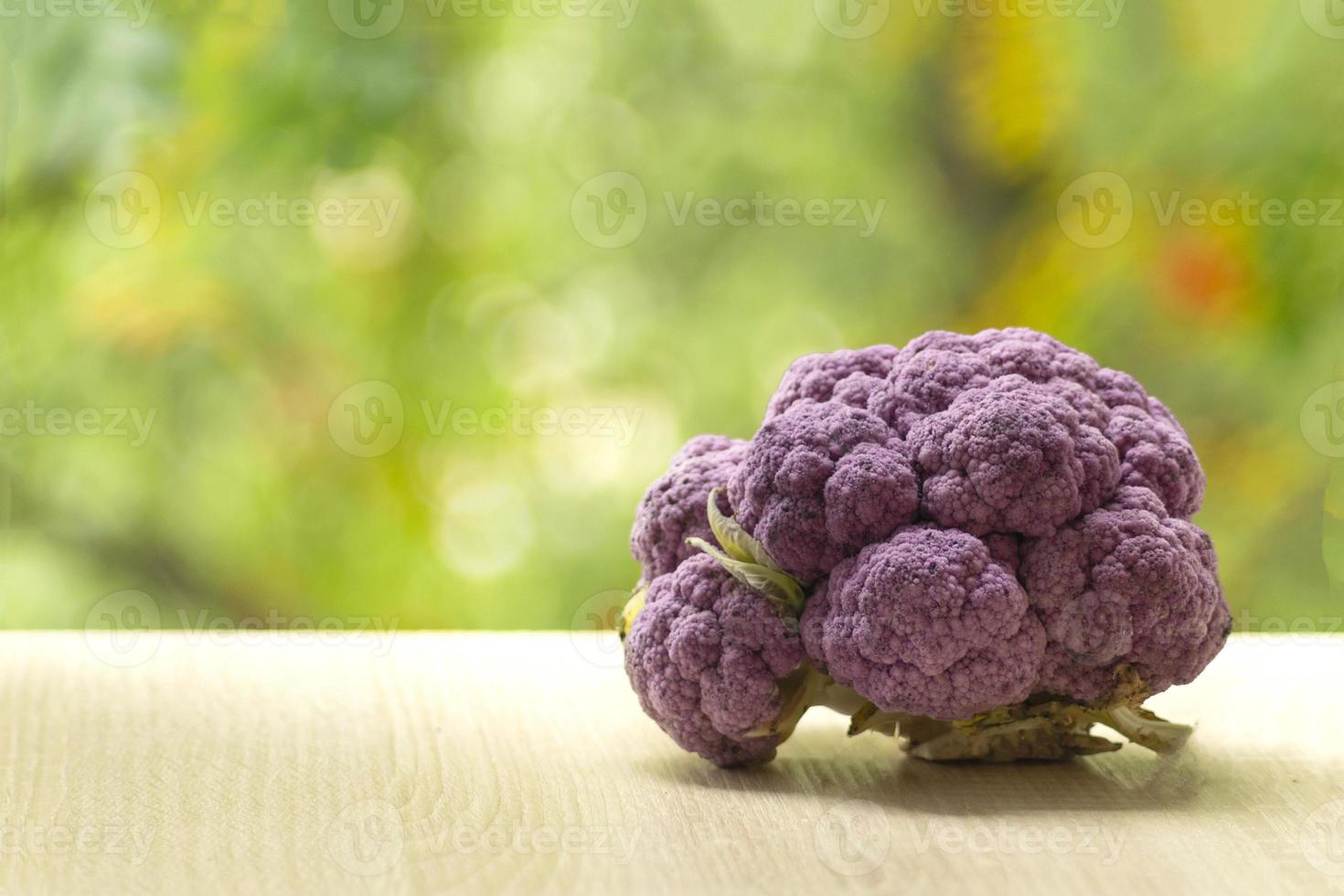 Fresh ripe purple cauliflower. Healthy food on table on defocus autumn background. photo