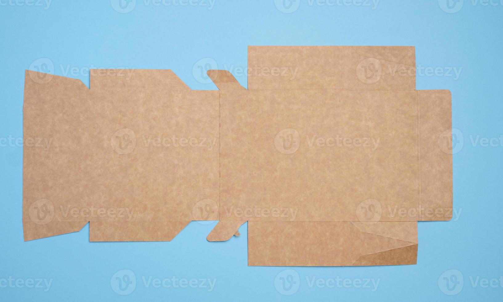 A brown cardboard box in an unfolded state on a blue background, food packaging, merchandise, top view photo