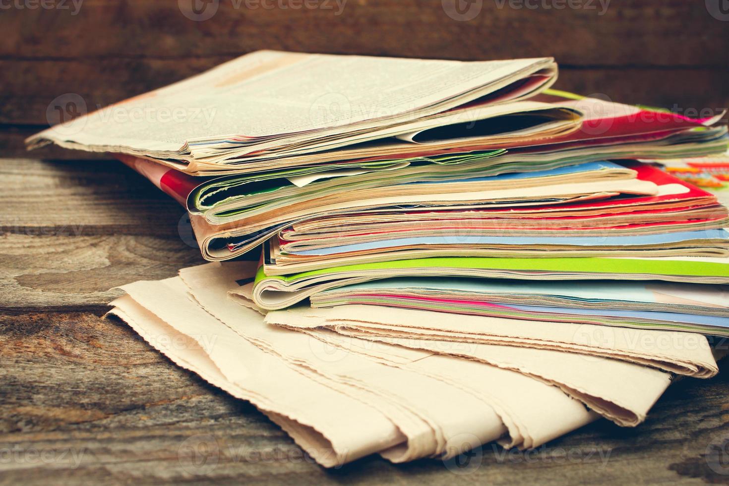 Newspapers and magazines on old wood background. Toned image. photo