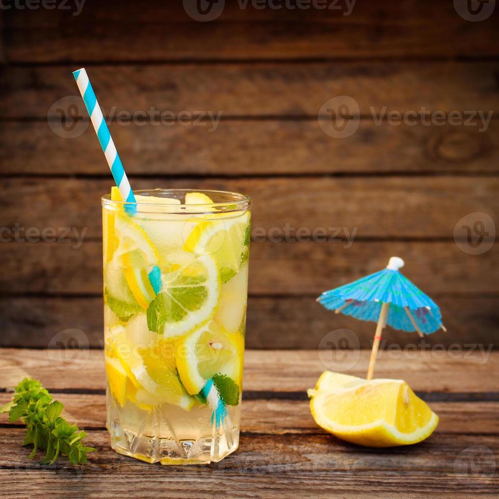 Drink with lemon, mint, ice, water on wooden background. Toned image photo