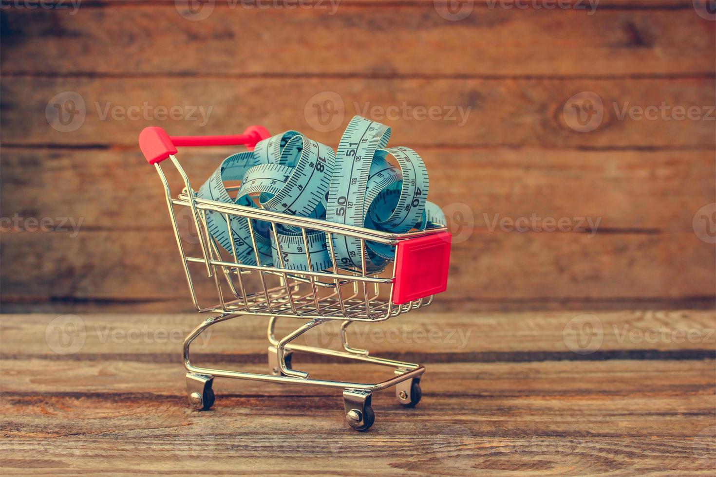 Shopping cart with tape line on old wood background. Toned image. photo