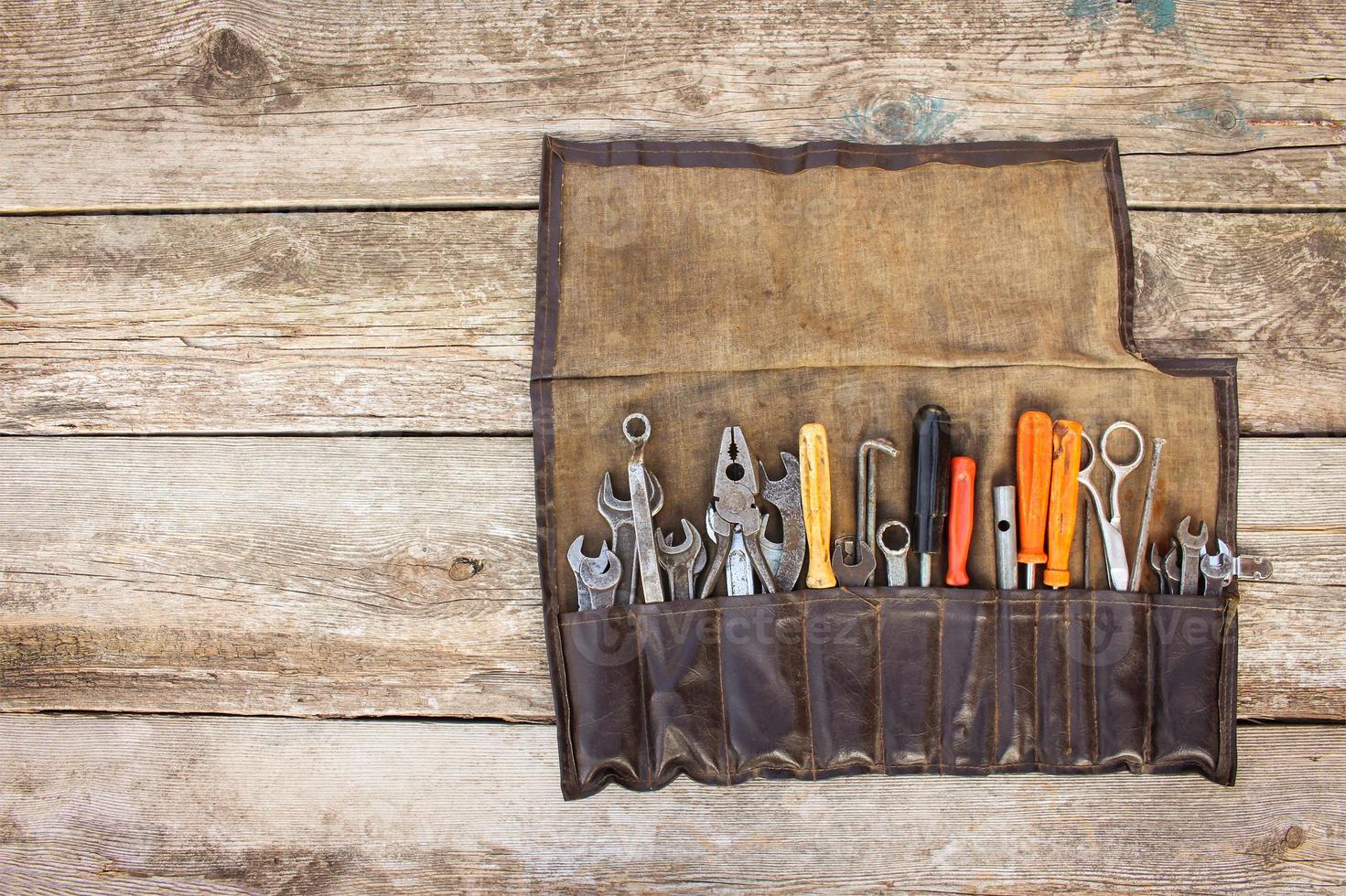 Old tools in bag on wooden background. Top view photo