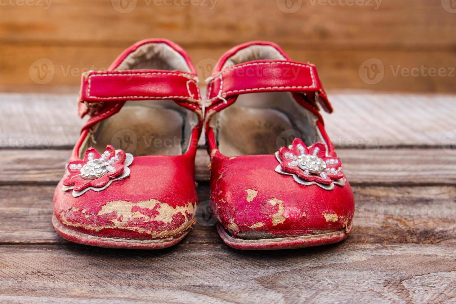 Old red baby shoes on wooden background. photo