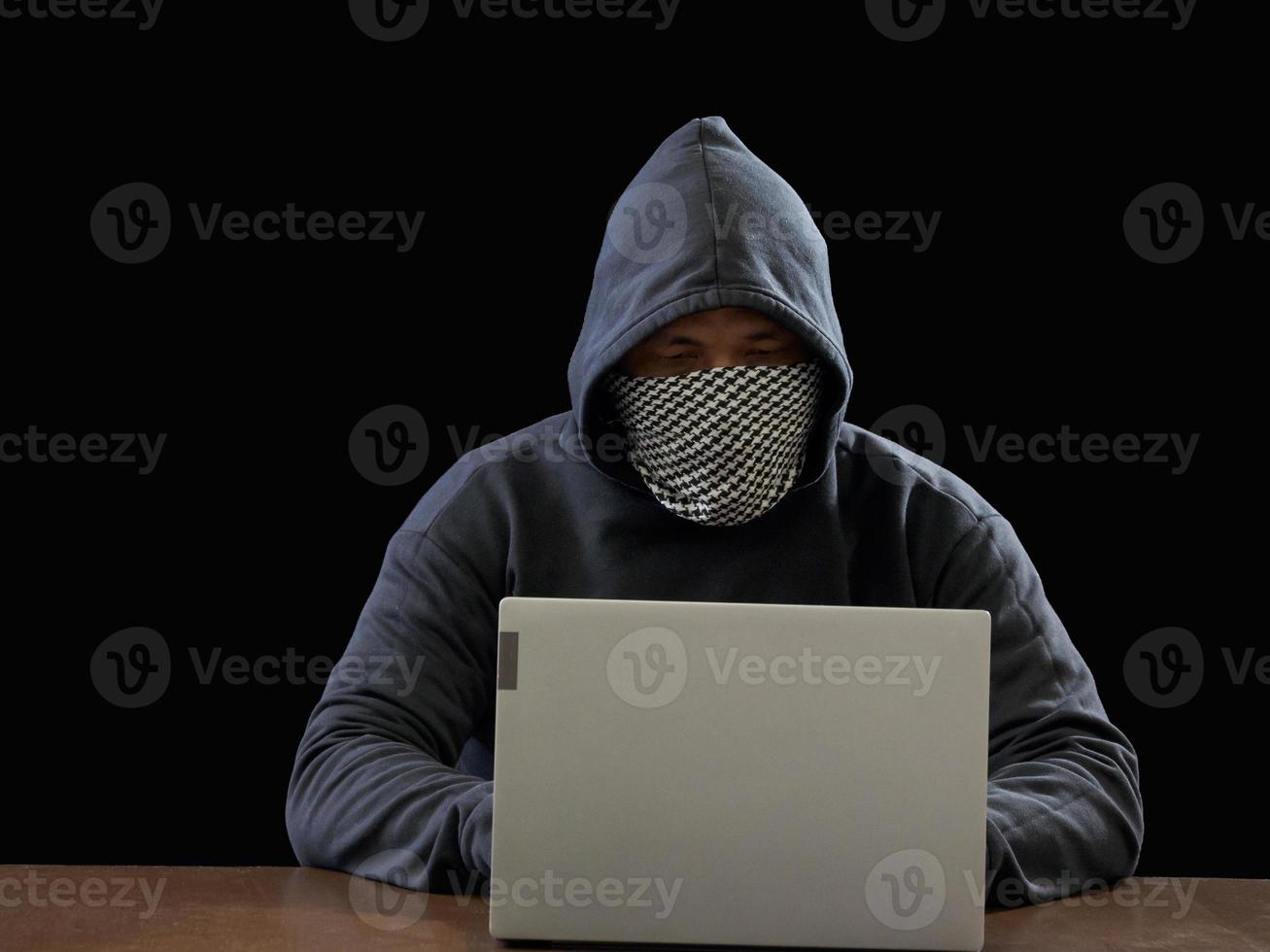 Hacker spy man one person in black hoodie sitting on a table looking computer laptop used login password attack security to circulate data digital in internet network system, night dark background. photo