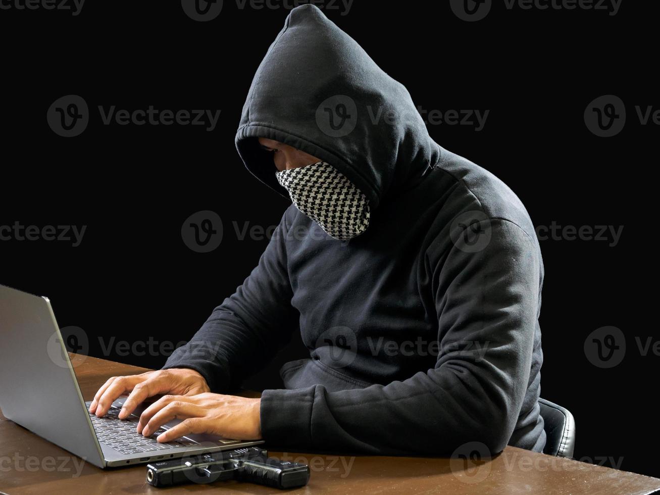 Hacker spy man one person in black hoodie sitting on a table looking computer laptop used login password attack security to circulate data digital in internet network system, night dark background. photo