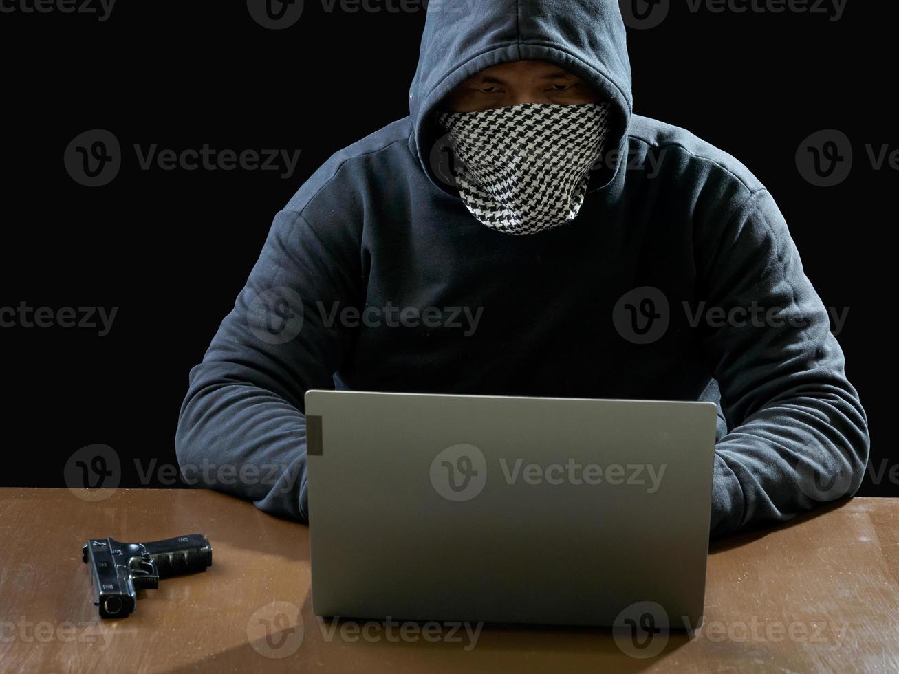 Hacker spy man one person in black hoodie sitting on a table looking computer laptop used login password attack security to circulate data digital in internet network system, night dark background. photo