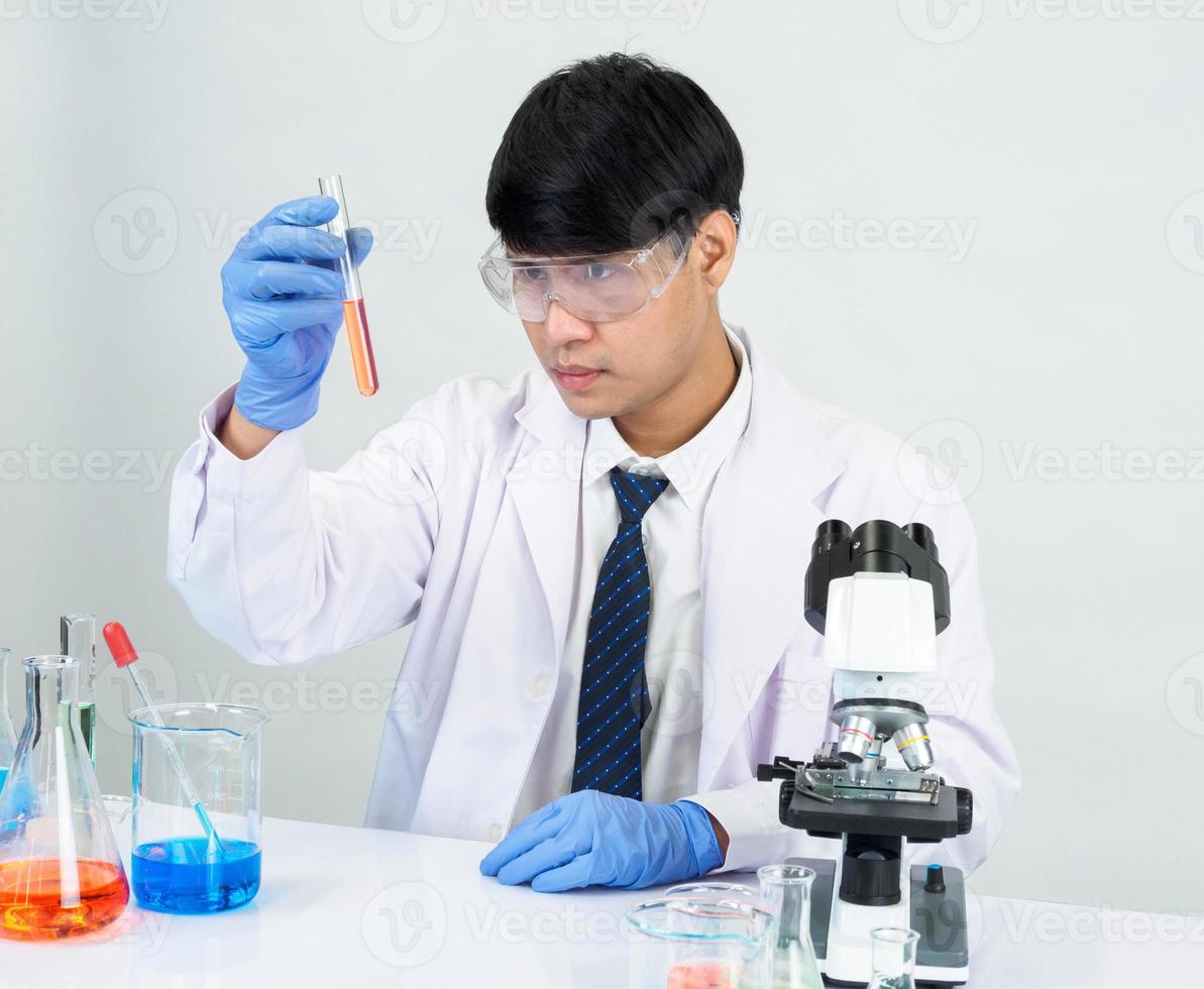 Asian male student scientist in reagent mixing laboratory In a science research laboratory with test tubes of various sizes and microscopes. on the table in  laboratory chemistry lab white background. photo