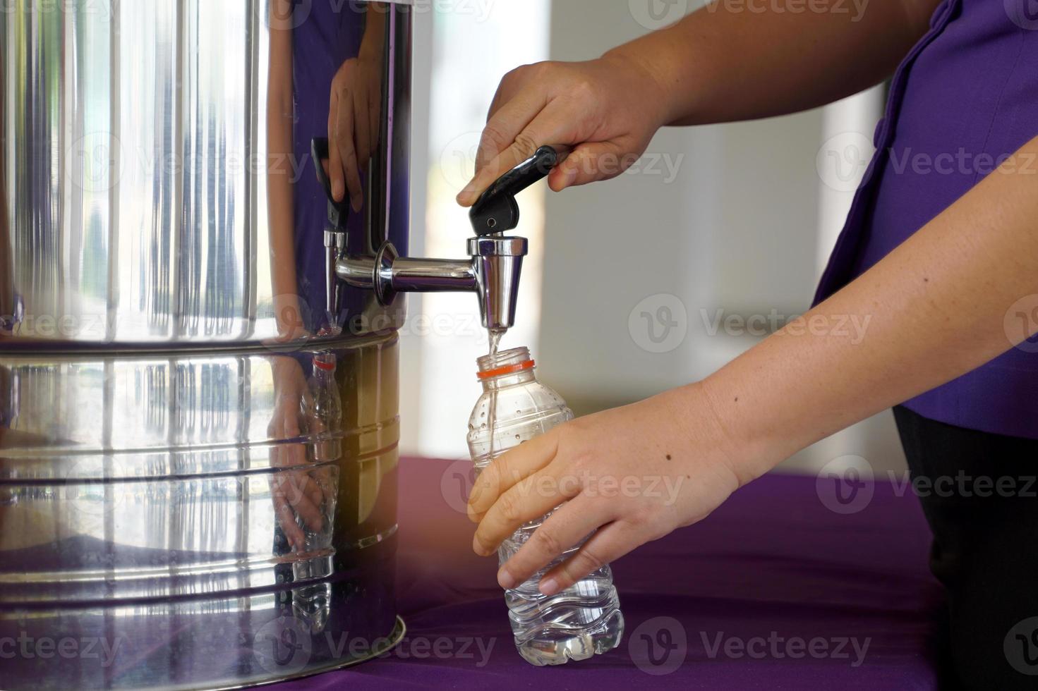 Turn on the cooler faucet. To add water to plastic water bottles that can be reused again when the water runs out, the concept of energy conservation, reuse, reduce, recycle, save energy. photo