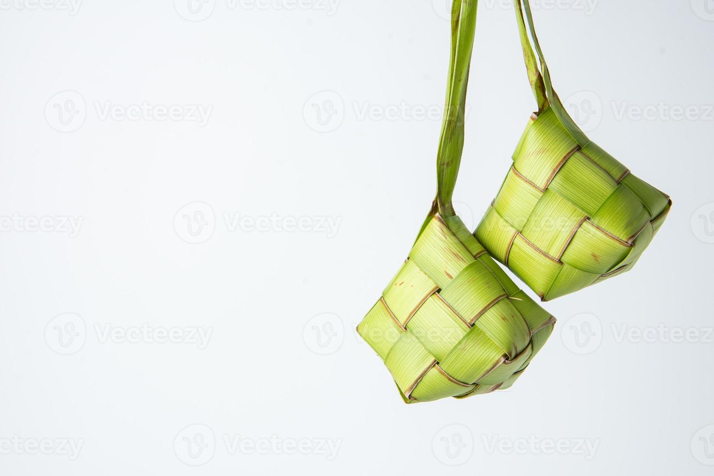 Ketupat lebaran is a typical Indonesian food during the festive season of Ketupat, Eid al Fitr, Eid al Adha, natural rice wrap made from young coconut leaves on a white background, empty space photo