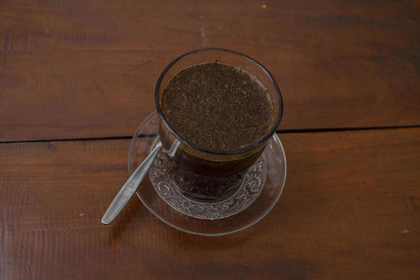 Close up photo a cup of arabica coffee with spoon from high angle. The photo is suitable to use for coffee shop background, menu poster and coffee content media.