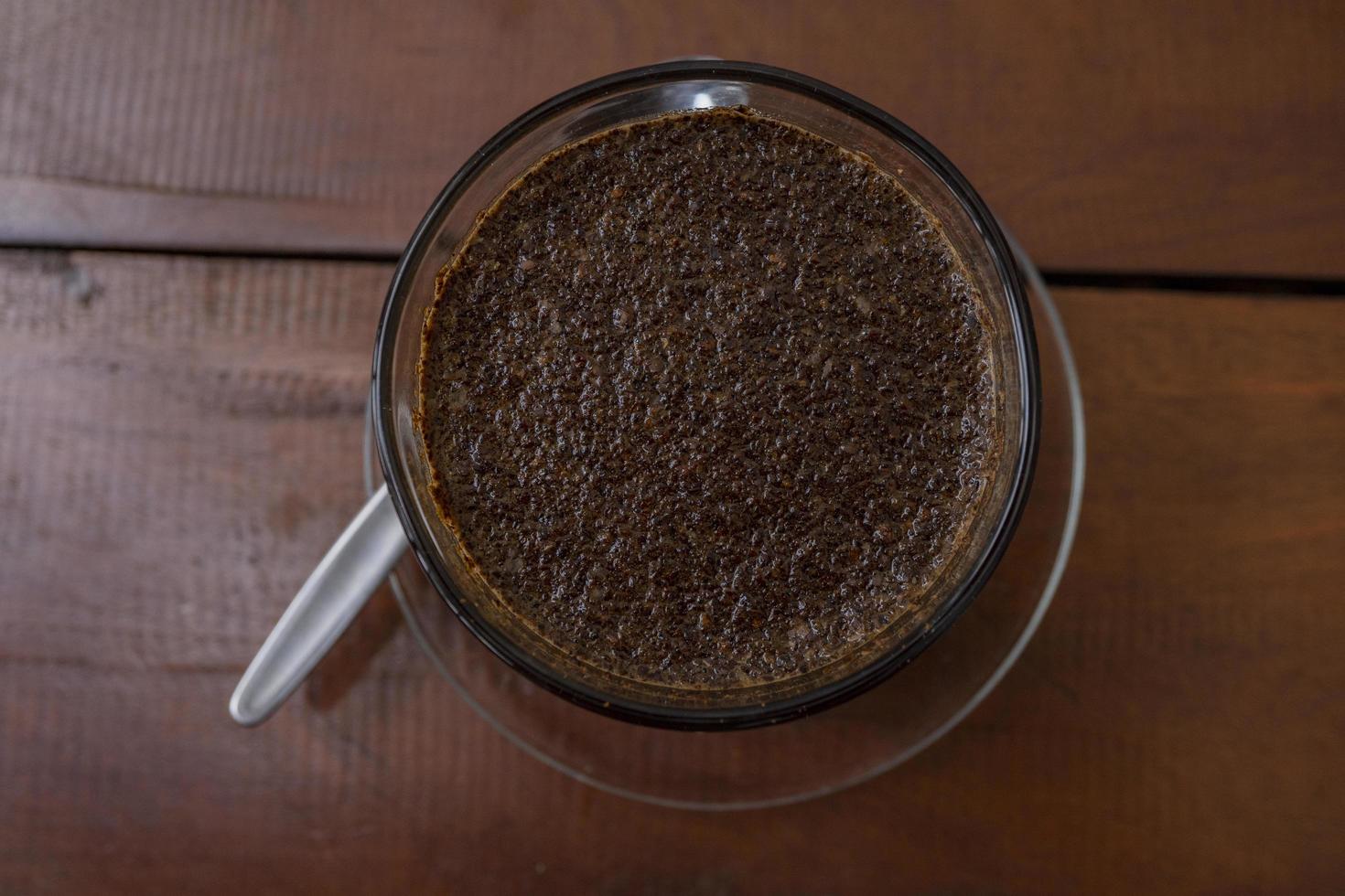 Close up photo a cup of arabica coffee with spoon from high angle. The photo is suitable to use for coffee shop background, menu poster and coffee content media.