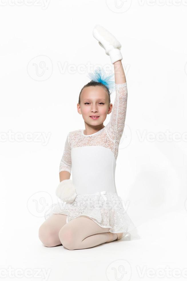 Girl ballerina in white ballet tutu skirt sitting on white background photo