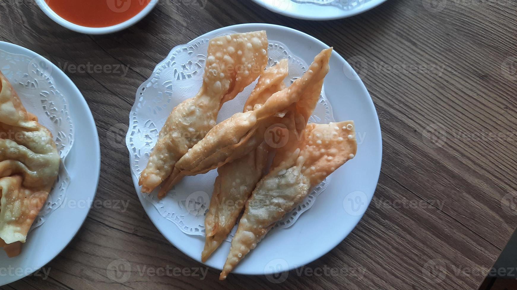 Pangsit, Pangsit Goreng, delicious Pangsit Ayam Goreng or Chicken Fried Dumpling, Indonesia Traditional Food made from flour and chicken, served on white sauce. photo