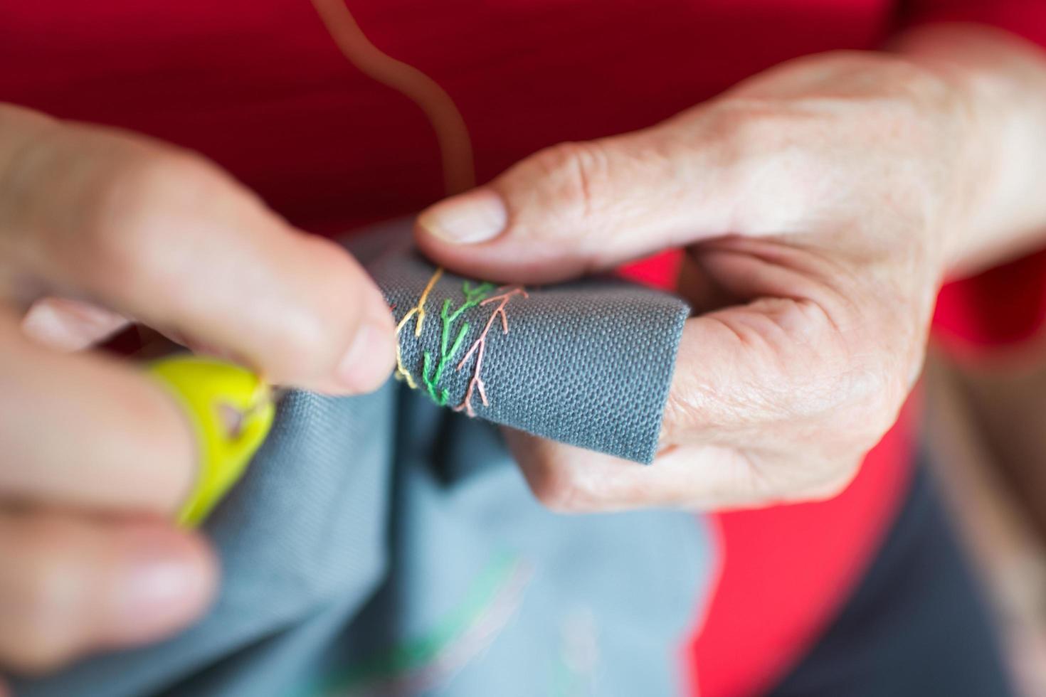 Close up of senior woman hands sewing at home photo