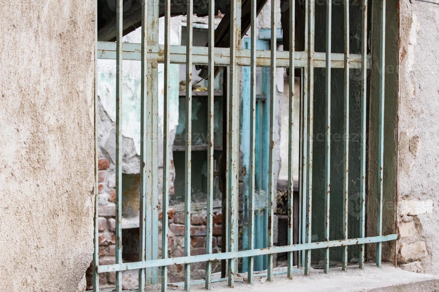 window with an iron fence in the stone house, security blue fences bars on the window photo