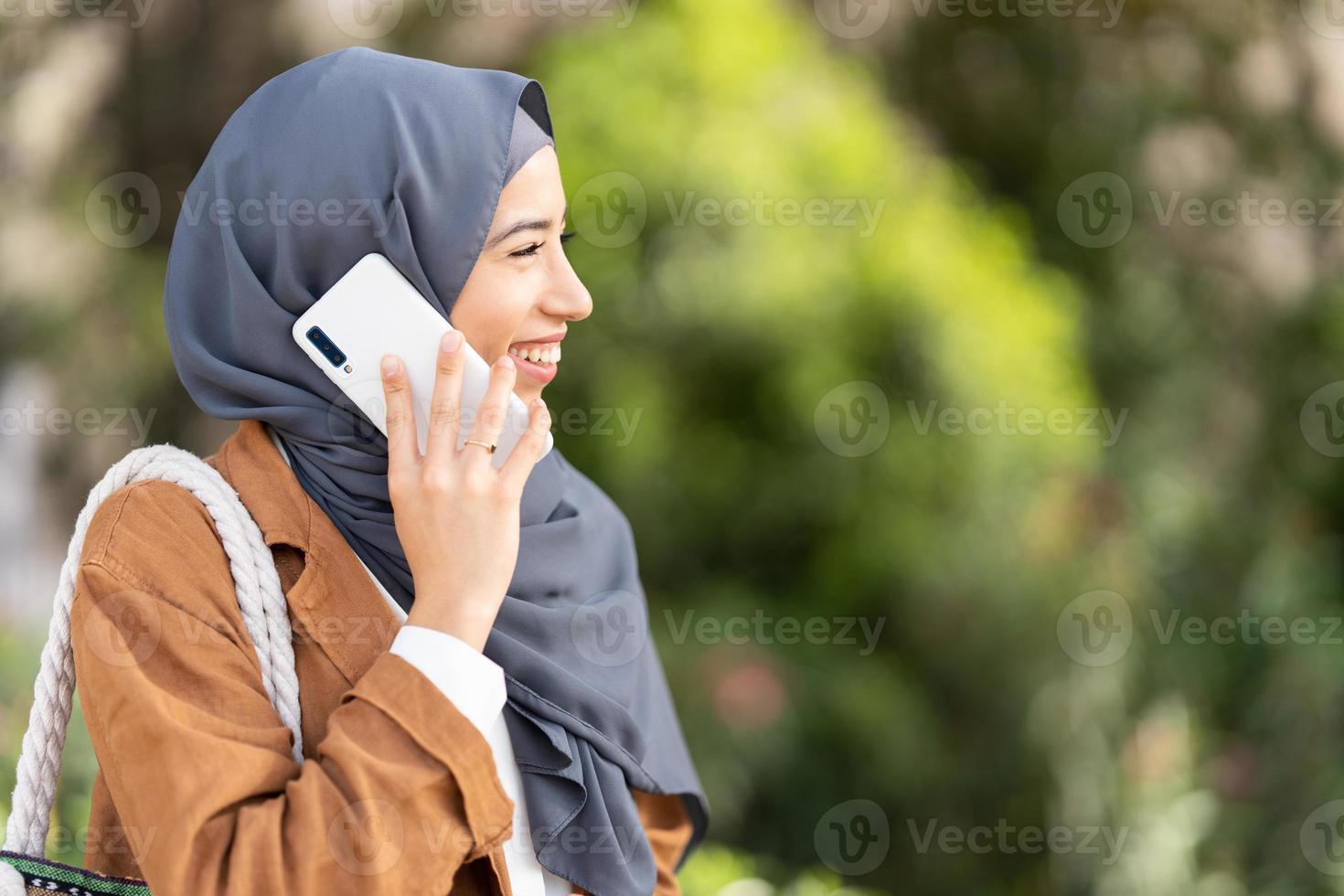 Profile of muslim woman smiling while talking to the mobile photo