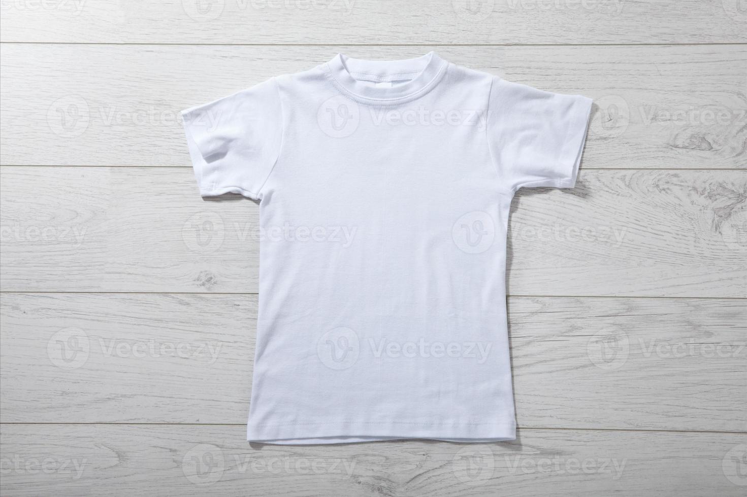 Front views on boys t-shirts on white wooden desk background. Mockup for design closeup photo