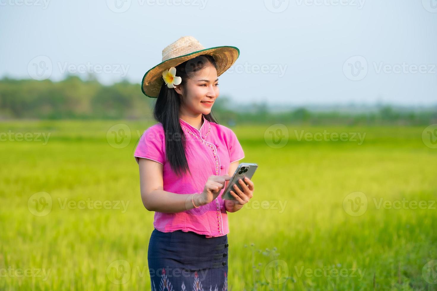 Asian female farmer holding tablet walking in rice field to store information photo