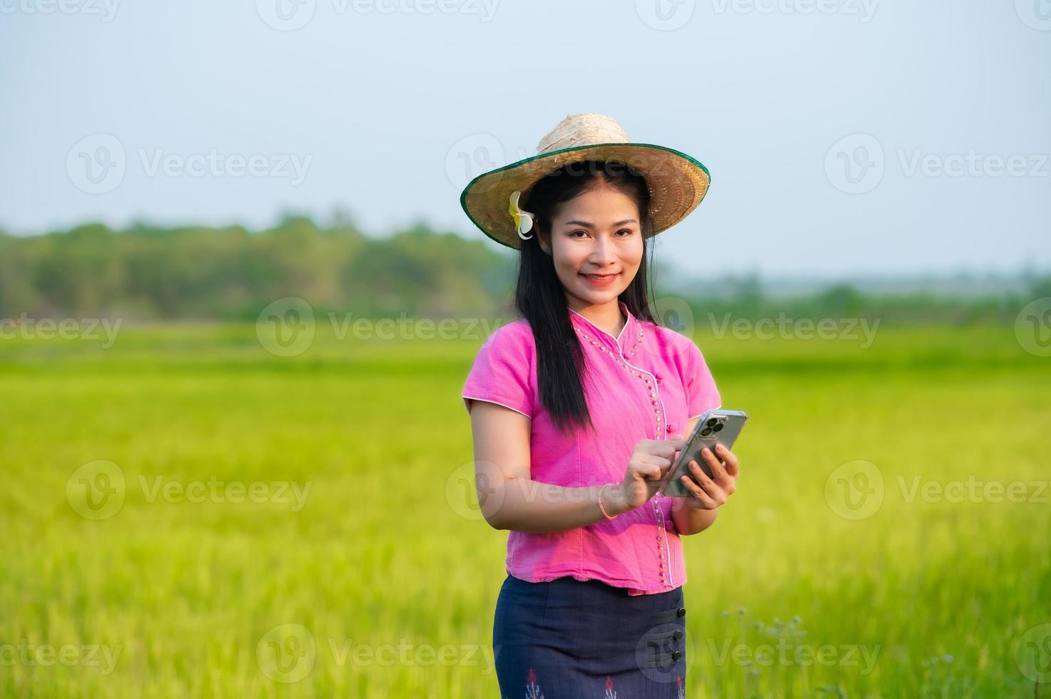 Asian female farmer holding tablet walking in rice field to store information photo