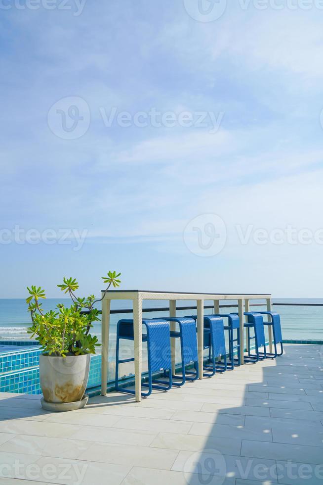 desk and bar stool near swimming pool with sea background 21957527