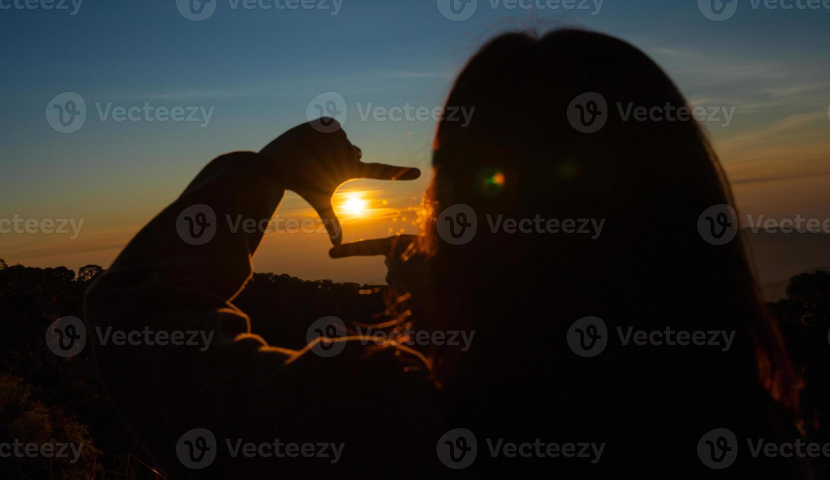 Future planning concept. Close up of woman hands making a frame sign over sunset sky. New year planning and vision. photo