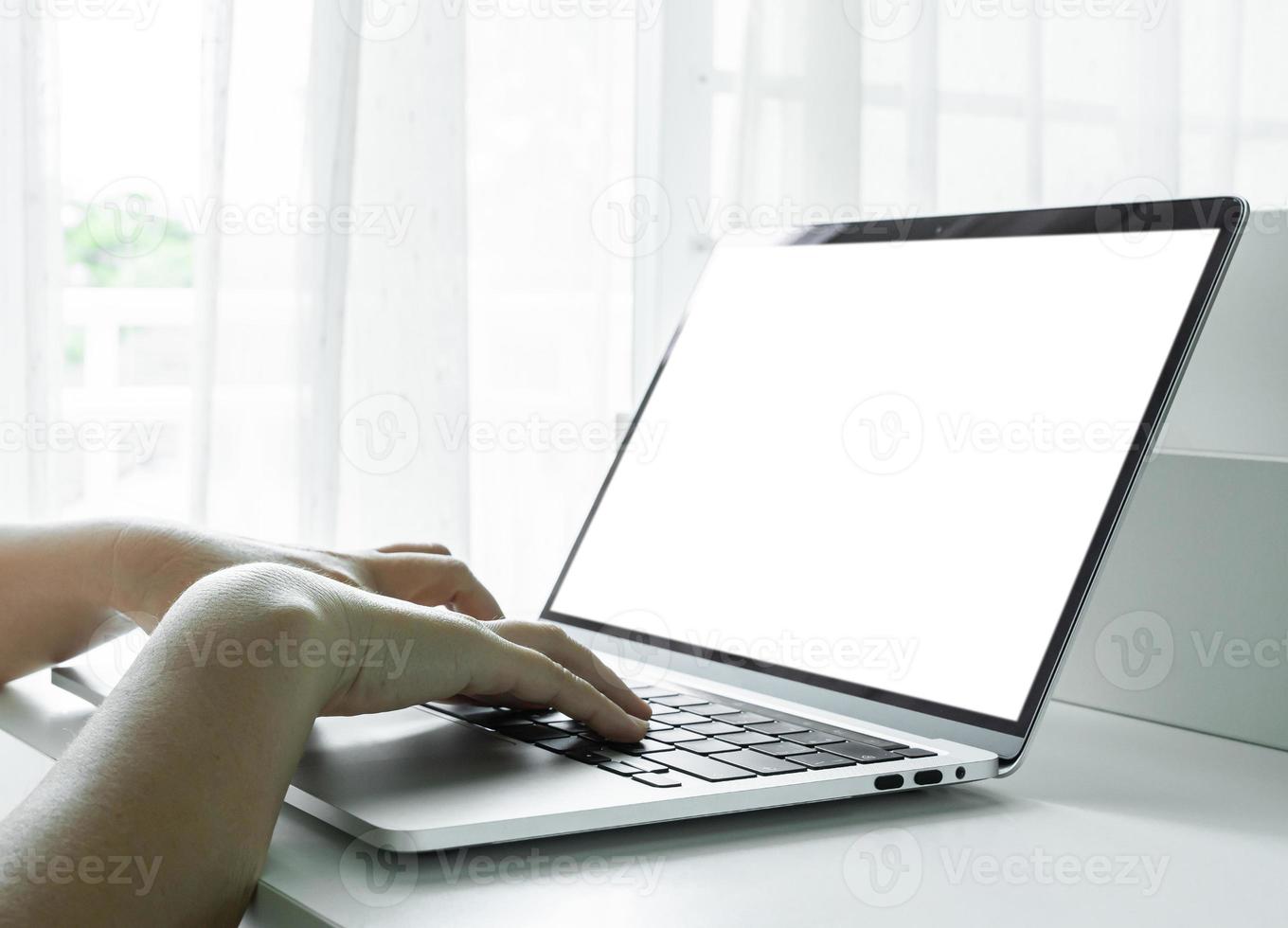 Woman hands using laptop with blank screen on white table at home or office. photo