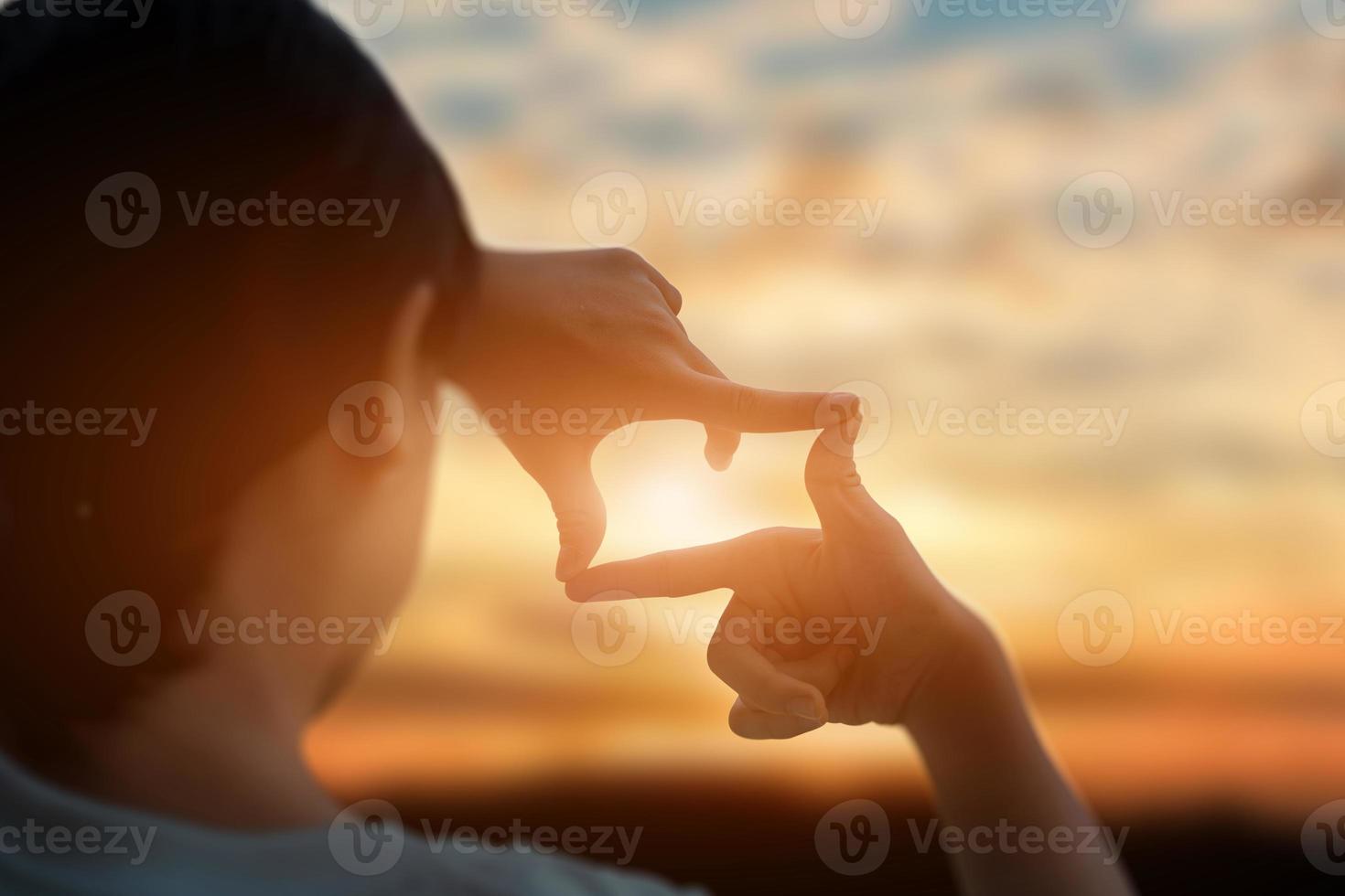 futuro planificación concepto. cerca arriba de joven mujer manos haciendo un marco firmar terminado puesta de sol cielo. nuevo año planificación y visión concepto. foto