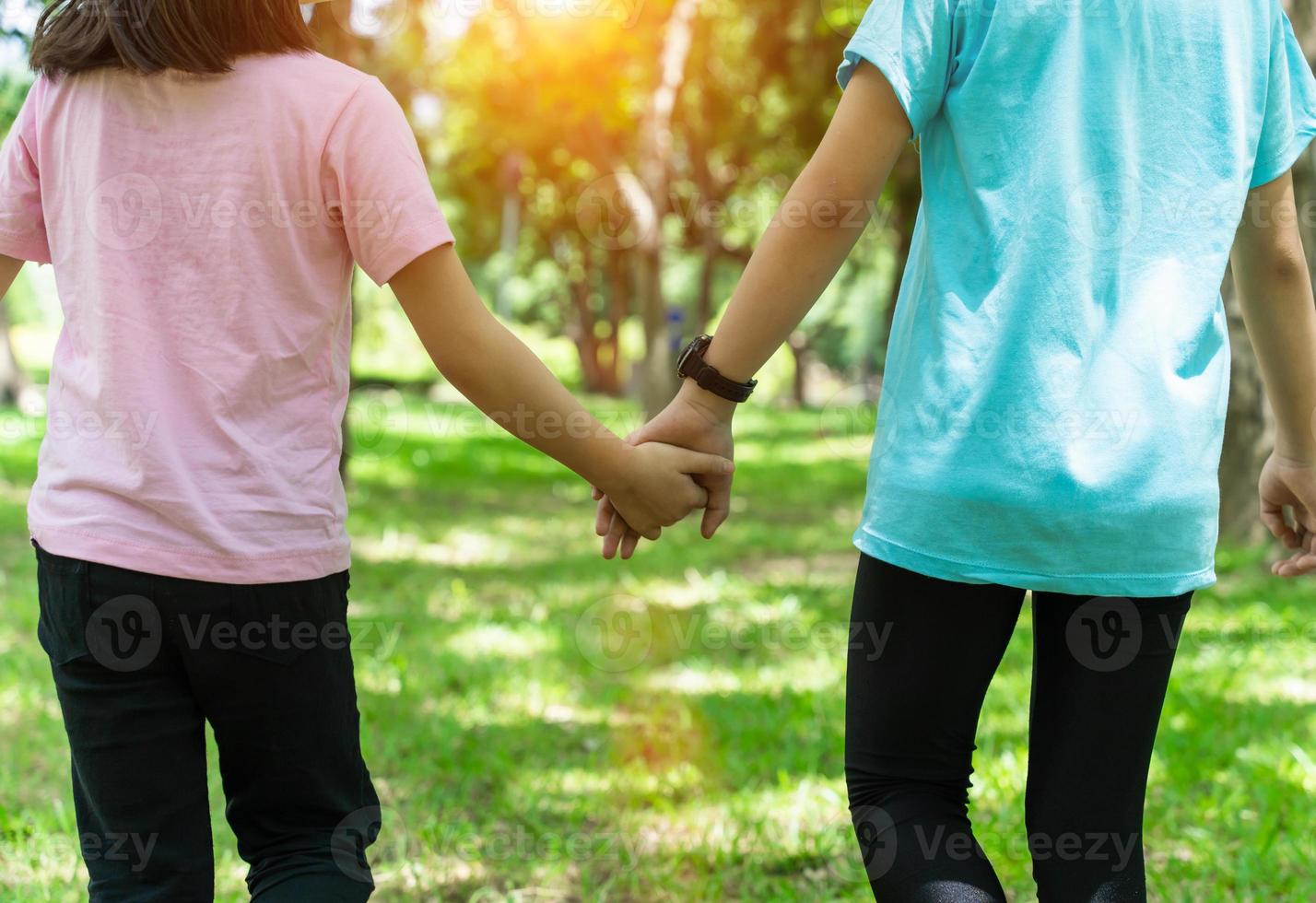 Two sister holding hands in the park in warm spring day. Happy friendship family concept. photo