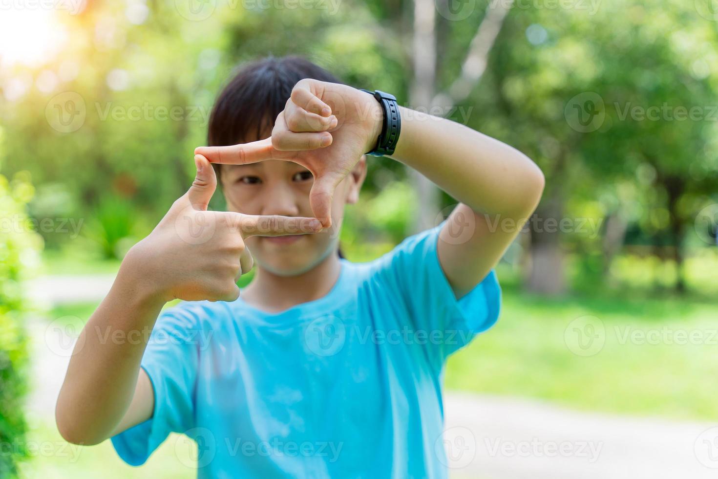 Close up of child girl smiling making frame with hands and fingers. Creativity and photography concept. photo