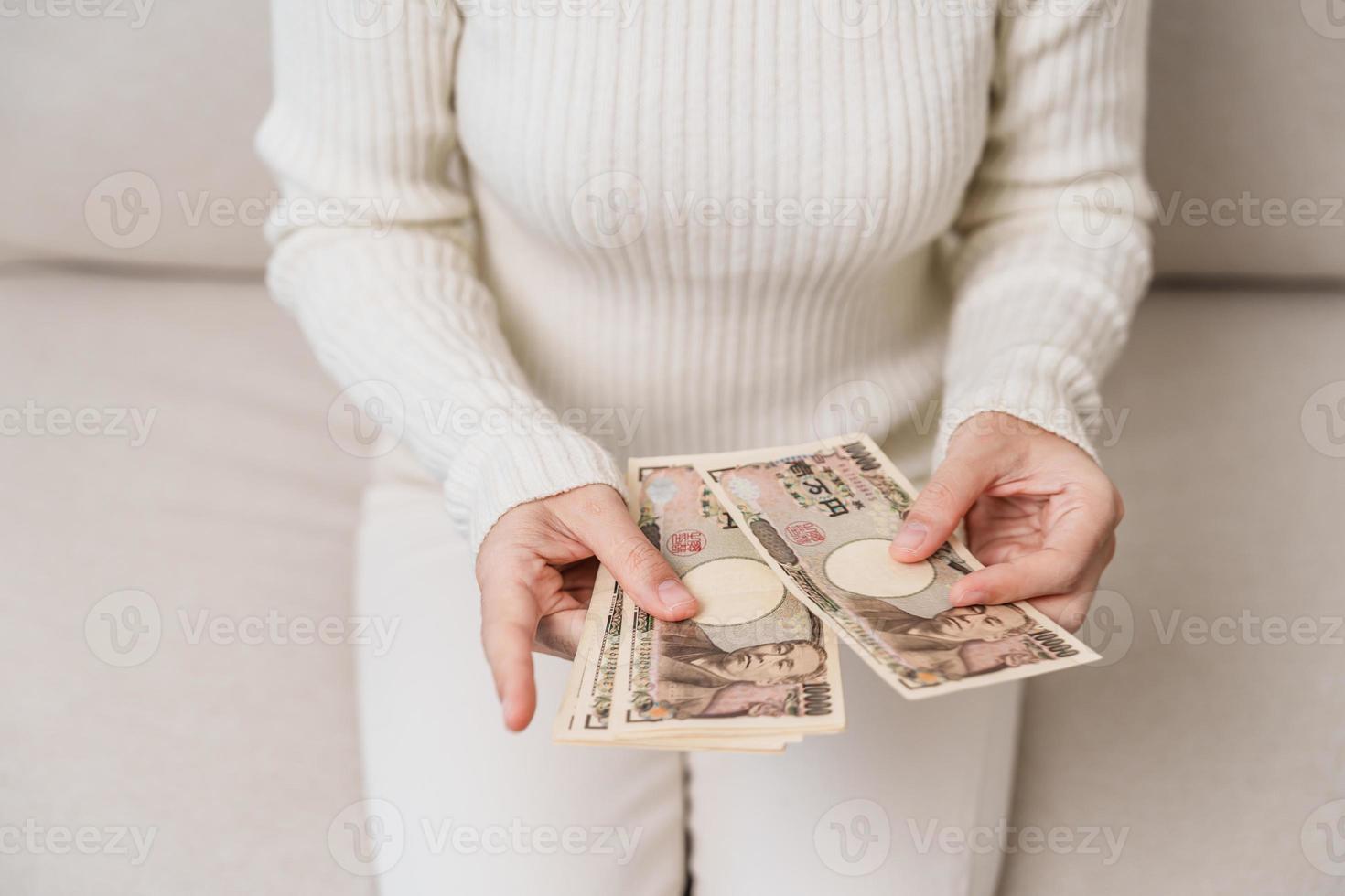 mano de mujer sosteniendo la pila de billetes de yen japonés. dinero de mil yenes. conceptos de pago en efectivo, impuestos, economía de recesión, inflación, inversión, finanzas y compras de japón foto