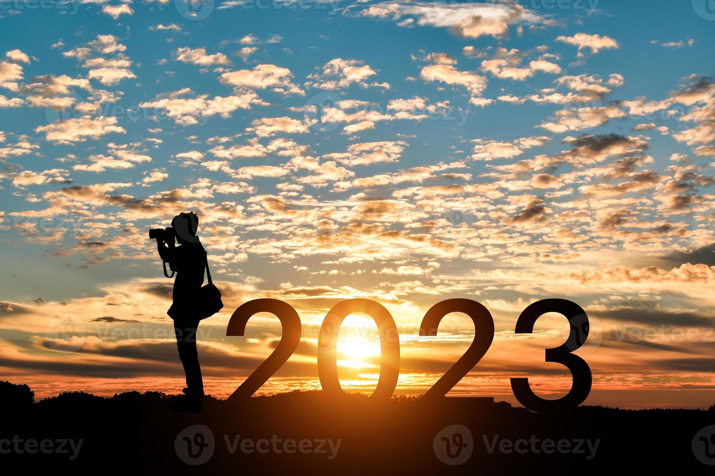 Silhouette of photographer taking photos in 2023 years at sunrise or sunset background. Idea for happy new year 2022.