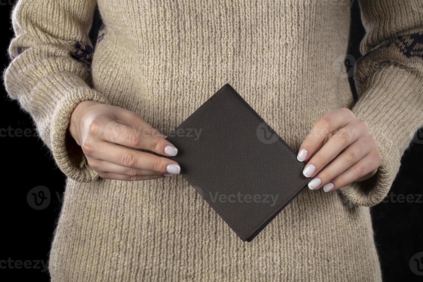 A brown leather wallet is in women's hands. photo