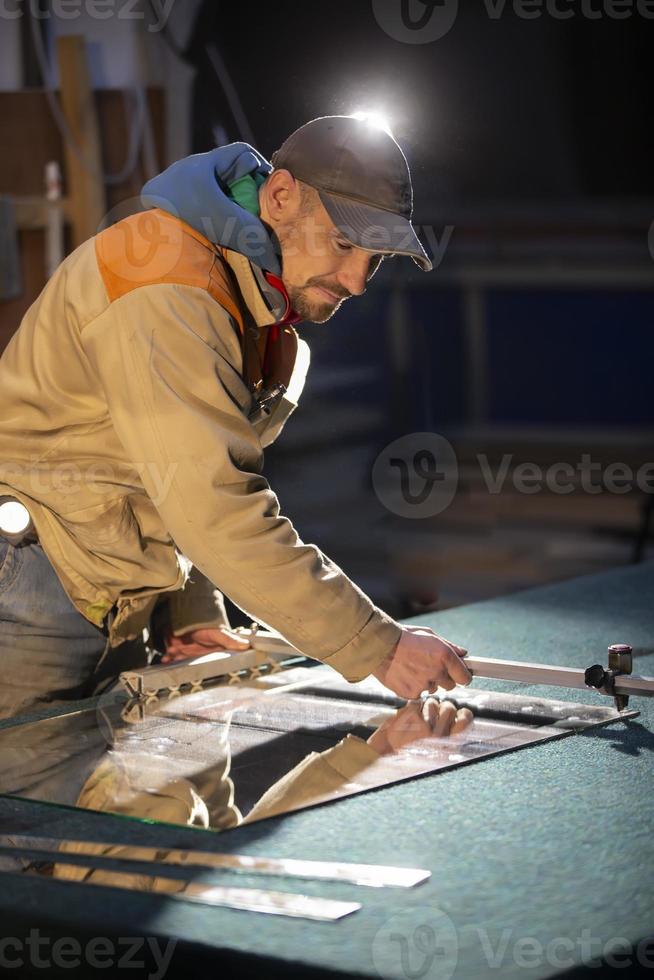 A working man cuts a mirror with a glass cutter. photo