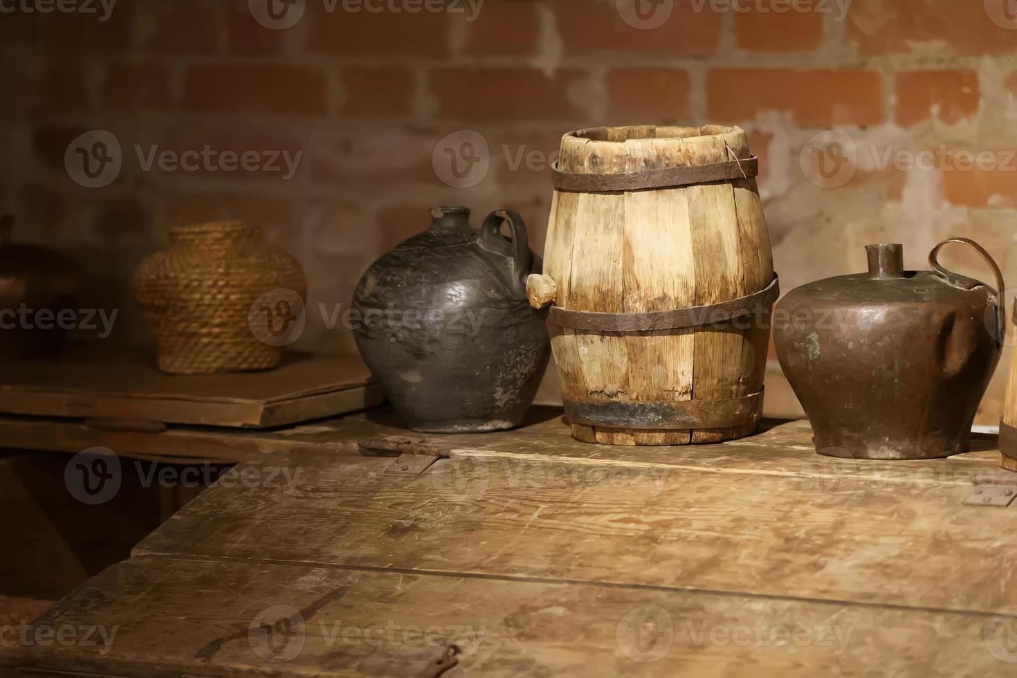 Retro jugs and a barrel in an old brick basement. photo