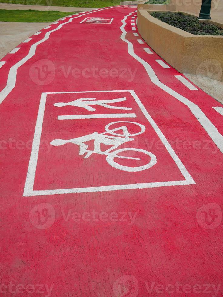 Perspective of Bicycle and pedestrian lane, track painted in red color and white line graphic sign, footpath, symbolic, sidewalk in the park, line markings photo