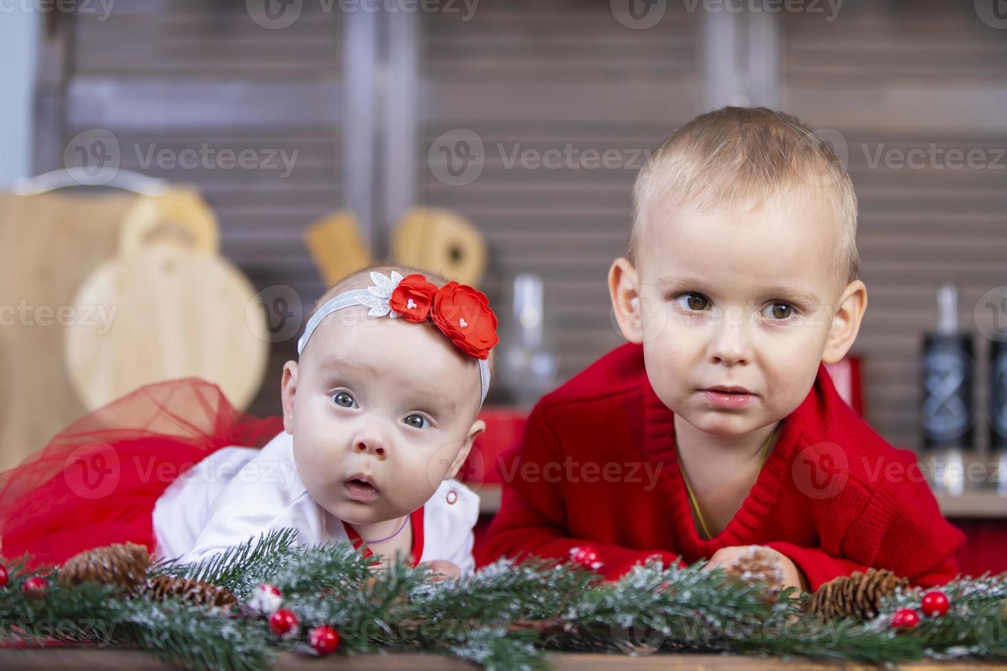 Little brother and newborn sister in a Christmas interior. Funny little children with Christmas decorations. photo