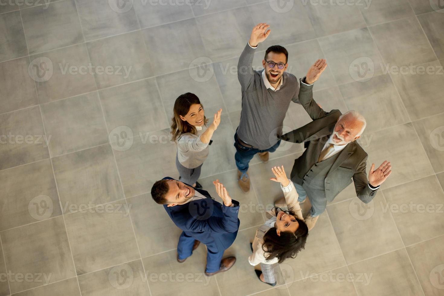 Aerial view at happy business people raise hands together with joy and success in the office hallway photo