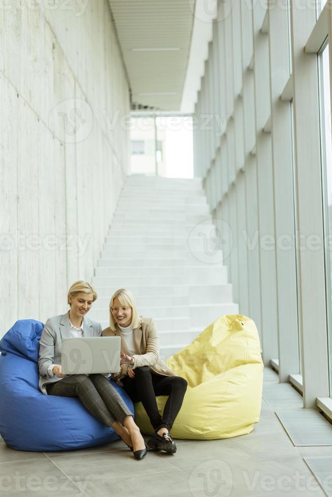 mujeres de negocios que usan computadoras portátiles en bolsas perezosas en la oficina moderna foto