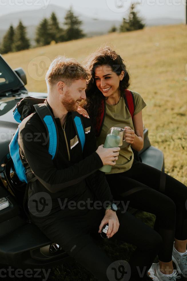 Young couple relaxing on a terrain vehicle hood at countryside photo