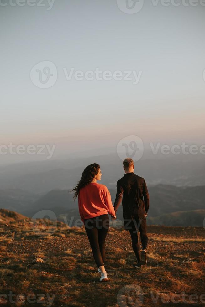 Smiling couple walking over green hills photo