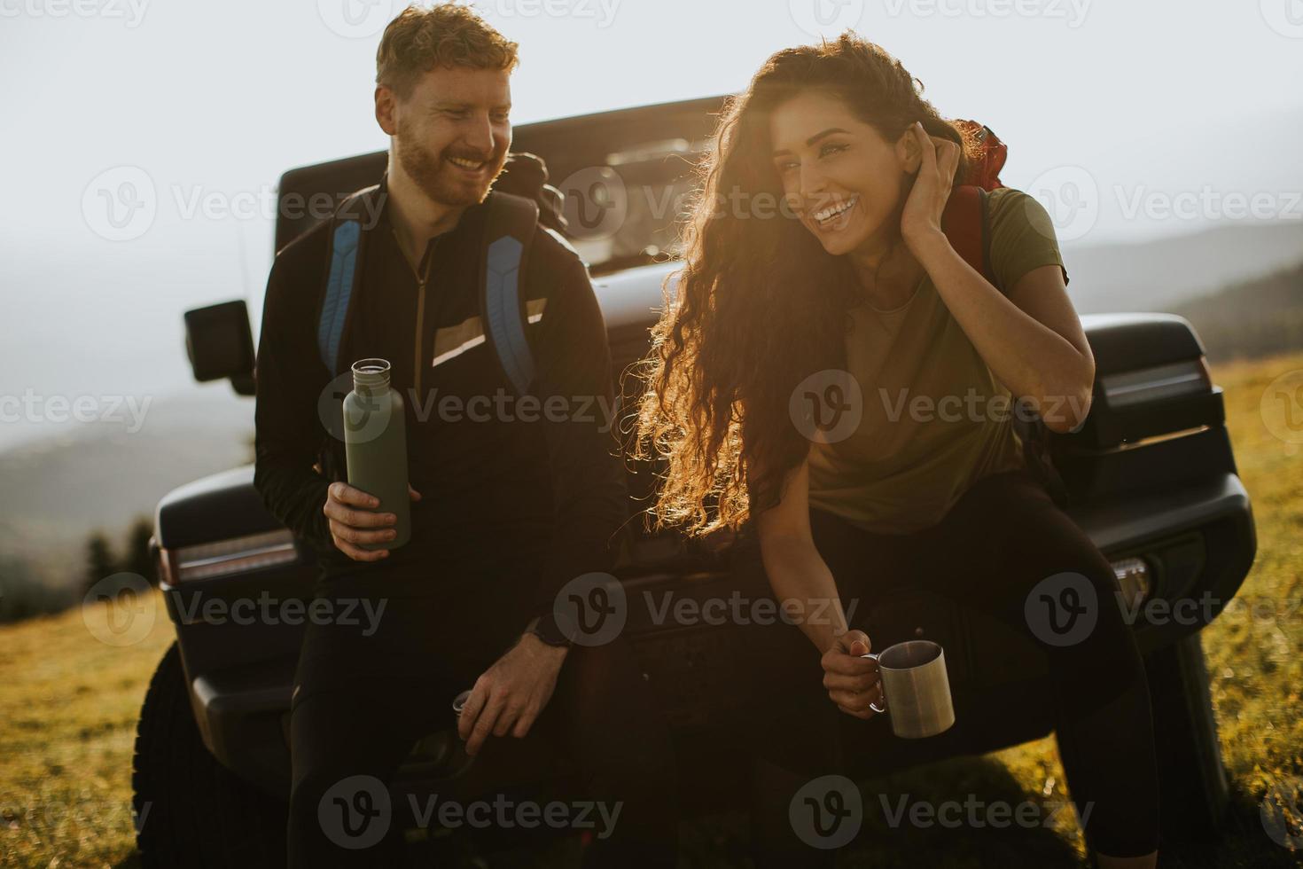 Young couple relaxing on a terrain vehicle hood at countryside photo