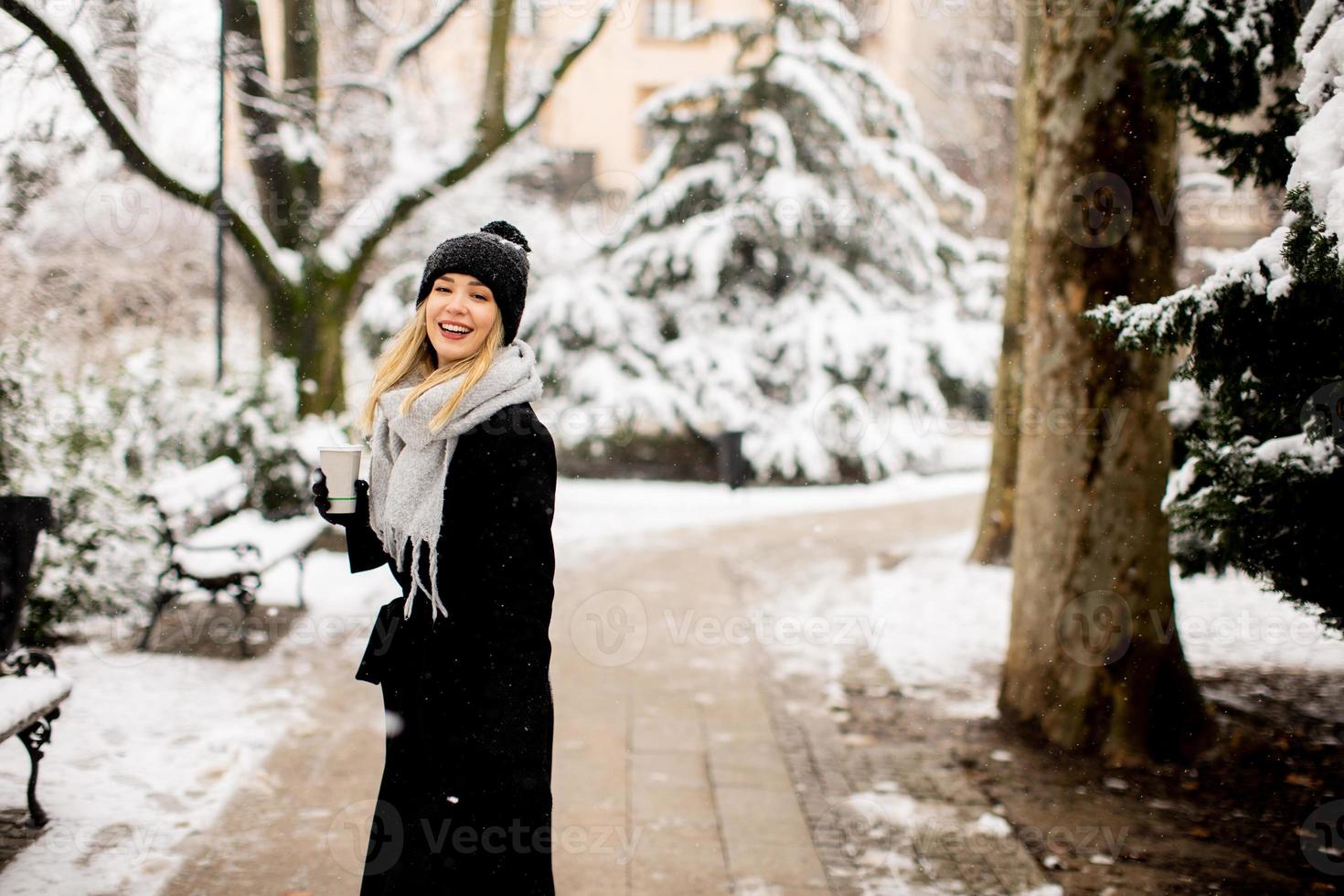 Young woman with Warm Clothes in Cold Winter Snow drinking coffee to go photo