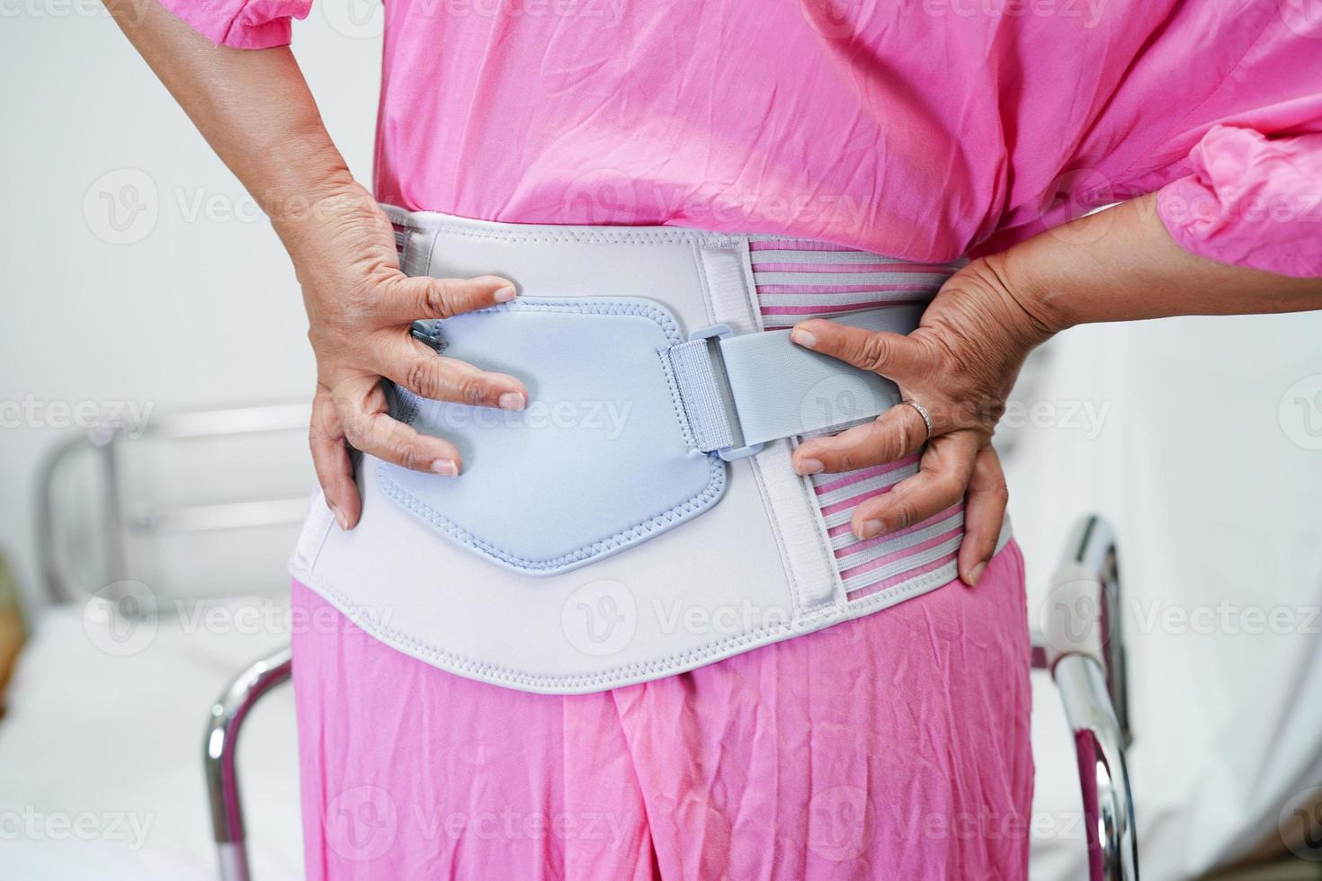 Asian senior pain back wearing elastic support belt with walker. photo