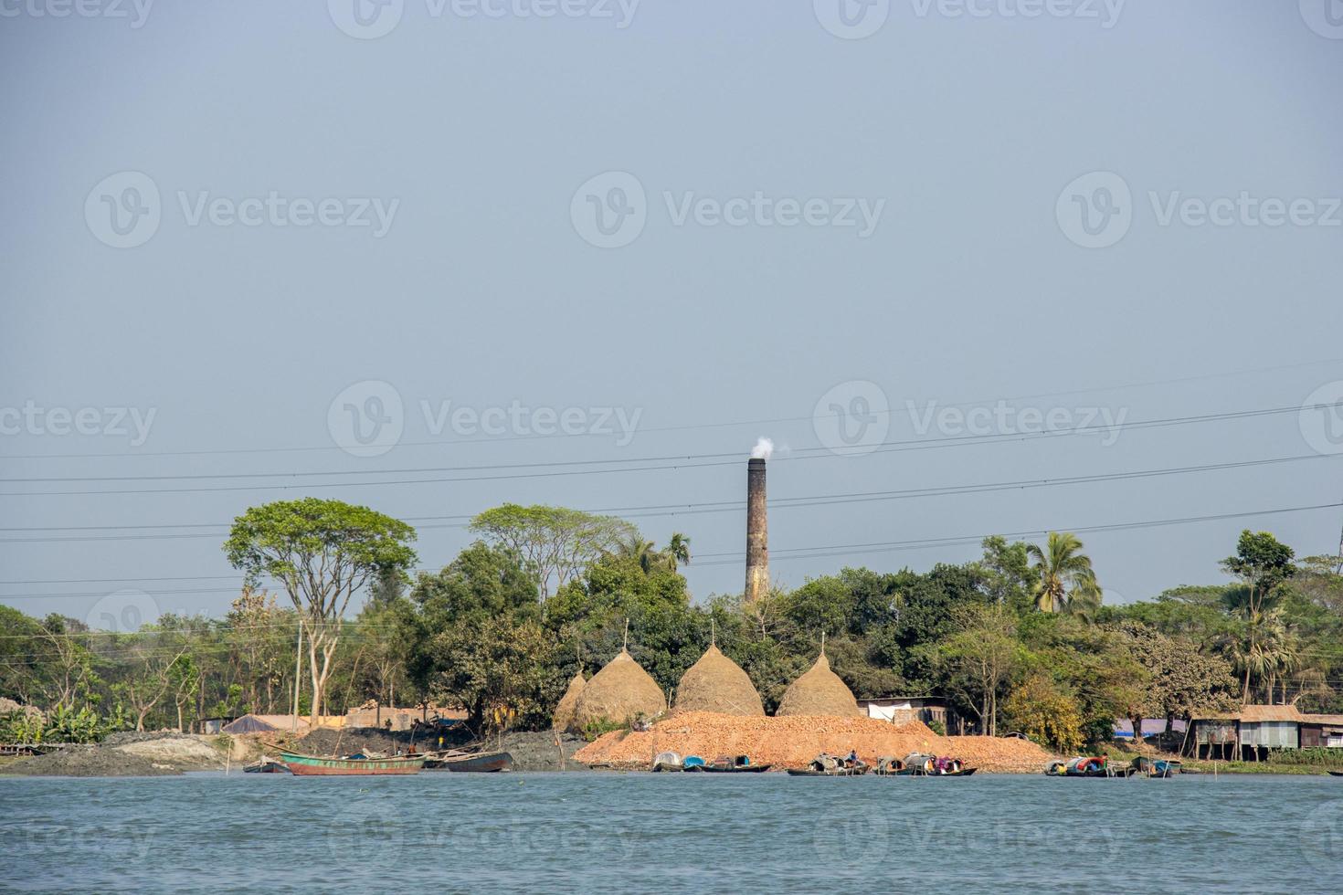 corriente de río escénico paisaje con un ladrillo horno. un hermosa rural zona en el banco de un río. barcos en el río y enorme pajar en el orilla del río. río y pueblo zona paisaje con azul cielo. foto